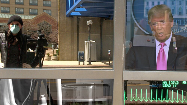 photo of the artist with a video camera reflected in a window with TV news in another frame of the window