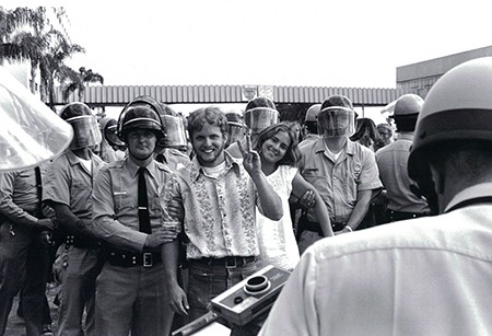 black and white photograph of two young people smiling while being arrested