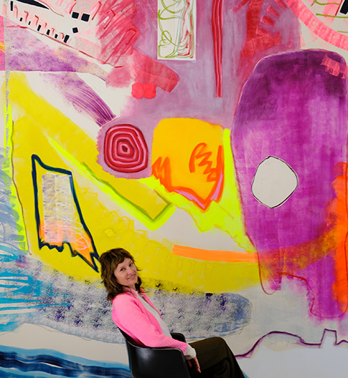Photo of Monique van Genderen in front of a large colorful painting