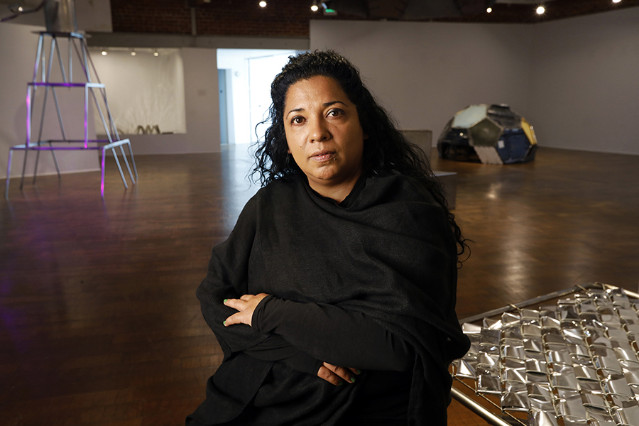 Photo of Beatriz Cortez in a large gallery with wooden floors and sculptures behind her.
