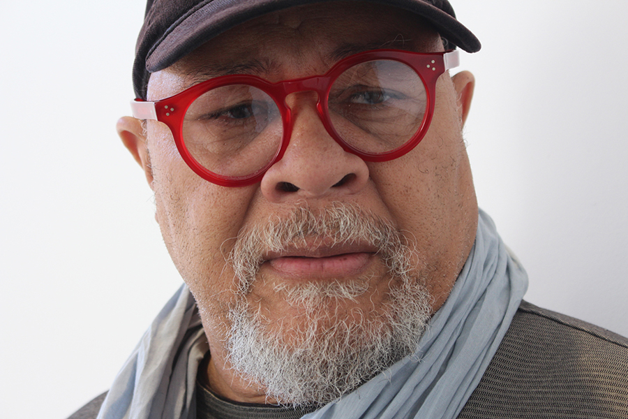 Photo of the artist in red framed glasses and hat