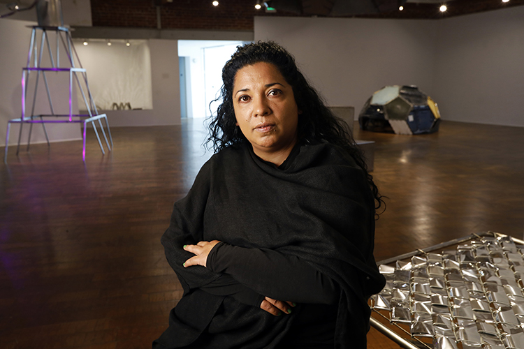 photo of the artist in a gallery with sculptures behind