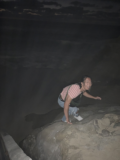 photo of the artist climbing a boulder at night, looking at the camera