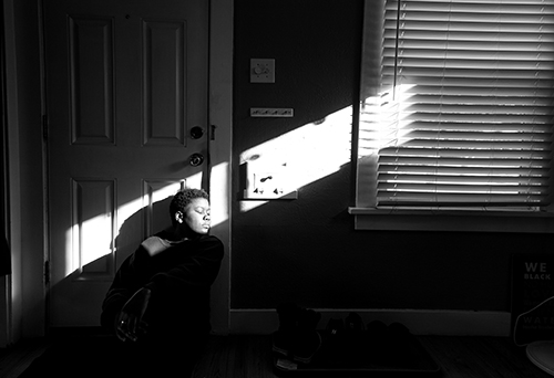 black and white photo of a person next to a window