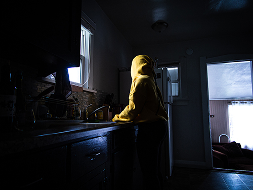 photo of a person in yellow hoodie at a kitchen sink